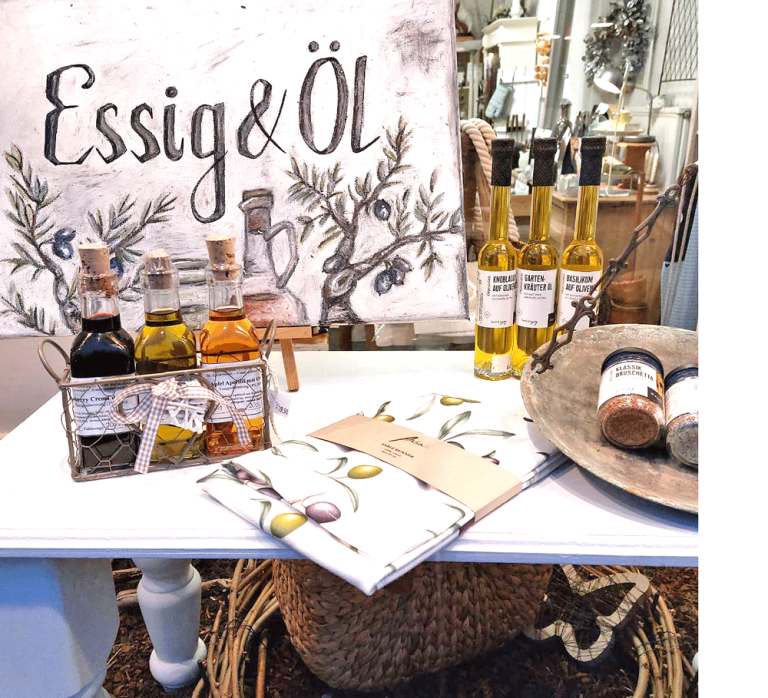 Verschiedene Sorten Essig integriert in harmonischer Schaufensterdekoration, mit Holz- und Kunstelementen kombiniert